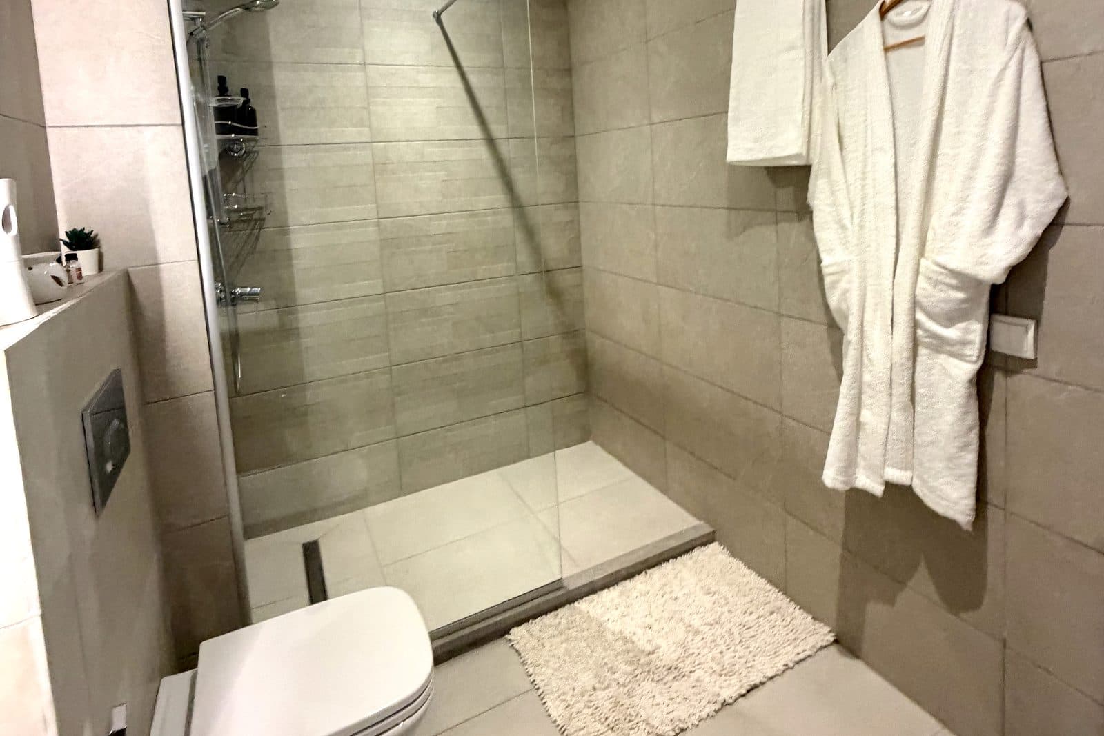 Salle de bain d'un logement géré à Marrakech, douche à l'italienne et peignoir en place avant l'arrivée des voyageurs