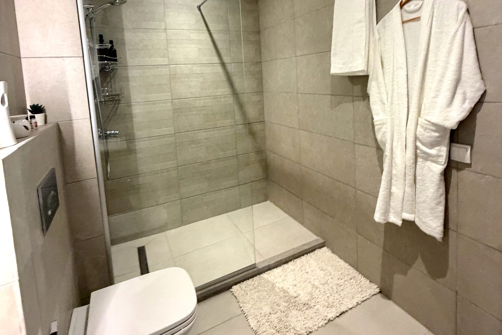 Salle de bain d'un logement géré à Marrakech, douche à l'italienne et peignoir en place avant l'arrivée des voyageurs