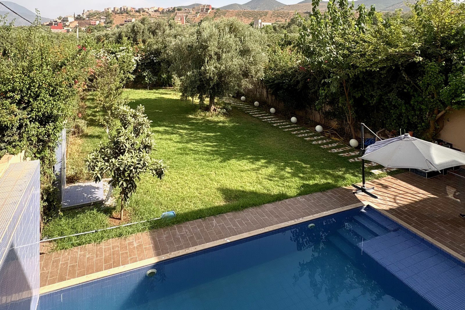 Jardin et piscine d'une villa à Marrakech, avec les collines en arrière-plan